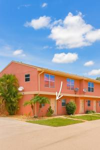 a large orange building with palm trees in front of it at Tropical Breeze Retreat in Fort Myers
