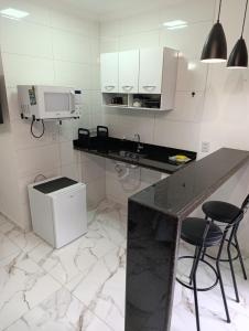 a white kitchen with a counter and two stools at Casa Nova Centro de Penedo-Quitinete in Penedo +4 photos