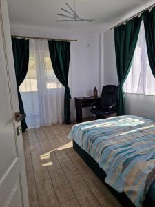 a bedroom with a bed with green curtains and a desk at Bucium Hills Retreat in Iaşi