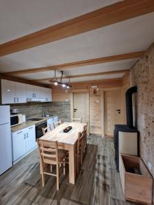 a kitchen and dining room with a wooden table and chairs at Brvnara Miris Bora - sa bazenom - in Šljivovica