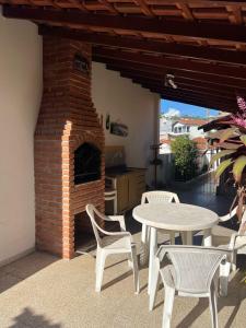 a patio with a table and chairs and a brick oven at Casa de Madeira Aconchego - Ótima localização in Águas de Lindóia