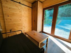 een kamer met een bed, een tafel en ramen bij Cabana Padurea Cerbilor in Moara de Pădure