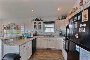 a kitchen with white cabinets and a black refrigerator at 4040 - Paws at the Beach in Kitty Hawk Beach +20 photos