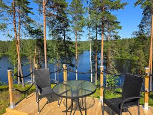a table and chairs on a deck with a view of a lake at Villa Runoranta - 11 hlö, Jämsä in Jämsä