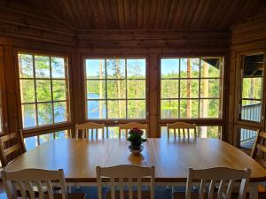 a large wooden table in a room with windows at Villa Runoranta - 11 hlö, Jämsä in Jämsä