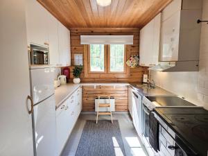 a kitchen with white cabinets and a wooden ceiling at Villa Runoranta - 11 hlö, Jämsä in Jämsä +21 photos