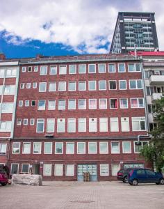 duży ceglany budynek z samochodami zaparkowanymi na parkingu w obiekcie MAC City Hostel w mieście Hamburg