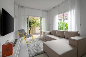 a white living room with a couch and a tv at OldTown Home Phuket 3min walk Central Festival in Ban Rangeng