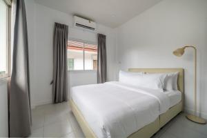 a white bed in a room with a window at OldTown Home Phuket 3min walk Central Festival in Ban Rangeng