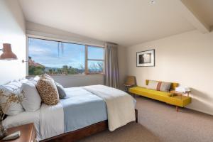 Un dormitorio con una cama y una ventana y un sofá. en Modern Mid-Century Retreat, en Dunedin
