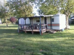 a small white trailer with a porch in a field at Camping à la Ferme de la Touche in Marennes