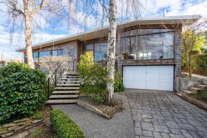 una casa de ladrillo con una puerta de garaje blanca en Modern Mid-Century Retreat, en Dunedin