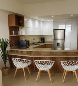 eine Küche mit einer Theke mit 2 Stühlen und einem Kühlschrank in der Unterkunft Apartamento Con Vistas En Ocean Blue Porlamar in Porlamar