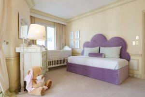 a bedroom with a large bed with a purple headboard at Hôtel Métropole Monte-Carlo in Monte Carlo