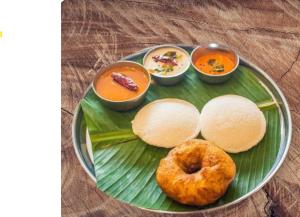 Un plato de comida con una dona en una hoja de plátano. en Koneru's Village Stay - Hampi "Workcation", en Munirābād 11 fotos más