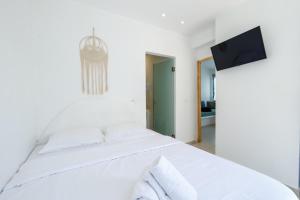 a bedroom with a white bed with a tv on the wall at Oldtown Suites Fira in Fira