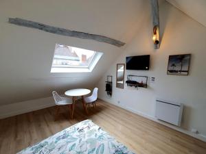 a room with a table and chairs and a tv at La cachette d Auxerre - Centre Ville in Auxerre