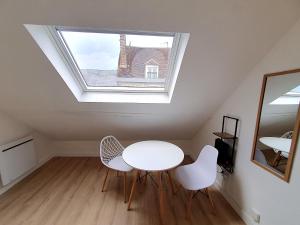 a room with a table and two chairs and a window at La cachette d Auxerre - Centre Ville in Auxerre