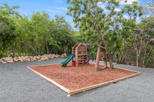 a playground with a slide and a tree at Vista Papaya Suites in Westpunt