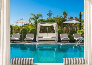 a view of a swimming pool with chairs and umbrellas at Hôtel Métropole Monte-Carlo in Monte Carlo