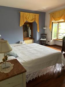 a bedroom with a large white bed with yellow curtains at Cascina Ciosse B&B in Grognardo