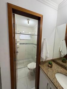 a bathroom with a toilet and a glass shower at Ap (Flat) Taperapuã Porto Seguro in Porto Seguro
