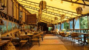 a restaurant with tables and chairs in a building at Akmenos Villas & Bungalow in Bražuolė