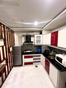 a small kitchen with red and white cabinets and appliances at Luxury 1BHK Apartment in Rawalpindi +7 photos
