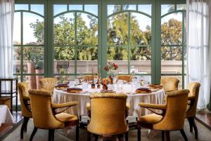 a dining room with a table and chairs and windows at Hôtel Métropole Monte-Carlo in Monte Carlo
