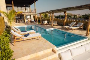 a swimming pool with chaise lounges next to a house at Aviva, brand new designer luxury villa in Vichayito