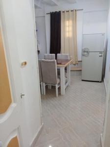 une cuisine avec une table et un réfrigérateur blanc dans l'établissement Roof 2 Bedrooms sea view Green Beach 150, à El Alamein