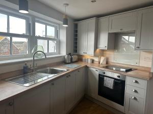 a kitchen with white cabinets and a sink at Church Walk View Apartment Filey in Filey