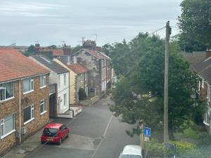 a street in a town with houses and a red car at Church Walk View Apartment Filey in Filey +5 photos