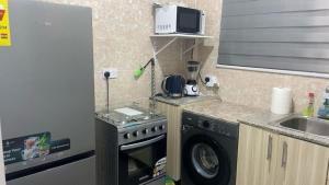 a kitchen with a washing machine and a microwave at Zebra apartment in Kwabenyan