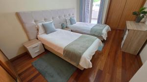 two beds in a room with wood floors at Penthouse Quinta Village Garajau in Caniço +65 photos