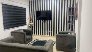 a living room with two chairs and a flat screen tv at Zebra apartment in Kwabenyan