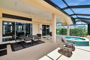 Marco Islandにある3 Bed 2 Bath Canal Home I Pool+Spa Gulf Accessのパティオ(テーブル、椅子付)、スイミングプールが備わります。