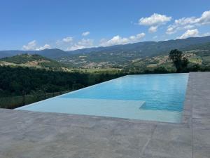 una piscina con le montagne sullo sfondo di Casale borgo le paline a Borgo alla Collina