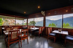 a restaurant with tables and chairs and large windows at Shola Heaven Resort in Kanthalloor