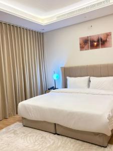a bedroom with a large white bed and curtains at شقه غرفه و صاله حي الملقا - نورسين in Quai