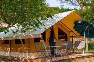 a yellow tent with chairs and an umbrella at Camping Onlycamp Les Premières Vignes in Savigny-lès-Beaune