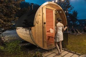 a woman standing in front of a wooden sauna at Gościna u Maryny & SPA pod Tatrami in Poronin