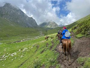 a group of people riding horses on a mountain trail at Aalam yurt camp Altyn-Arashan in Mineralʼnyy Istochnik Altyn-Arasan