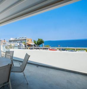 a balcony with a table and chairs and the ocean at Blue Horizon Suites in Kallithea Halkidikis
