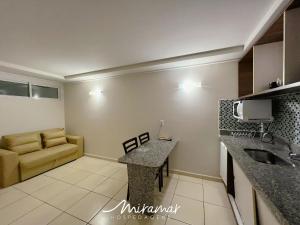 a living room with a couch and a kitchen at Blue Sunset Frente Mar Cabo Branco-Miramar Hospedagens in Penha