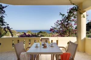 a table on a patio with a view of the ocean at Sunrise Hotel & Apartments in Rodakino