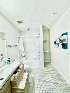 a white bathroom with a sink and a tub at Skyline Solace in Des Moines
