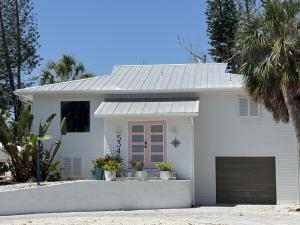 a white house with a garage and palm trees at Aylees Siesta Key Beach House-360 steps from beach-Saltwater Pool-Pet Friendly in Siesta Key