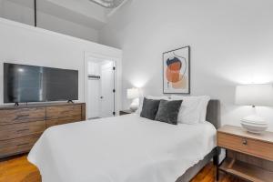 ein weißes Schlafzimmer mit einem großen Bett und einem Flachbild-TV in der Unterkunft Landing Apartments - Greenville in Greenville