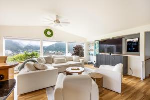 a living room with white furniture and a flat screen tv at Magical Mountain Retreat in Juneau